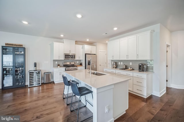 kitchen featuring a center island with sink, dark hardwood / wood-style flooring, white cabinetry, and appliances with stainless steel finishes