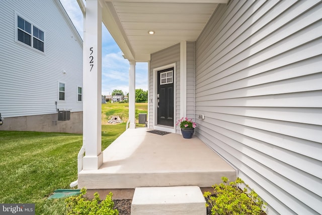 doorway to property featuring central AC unit, covered porch, and a lawn