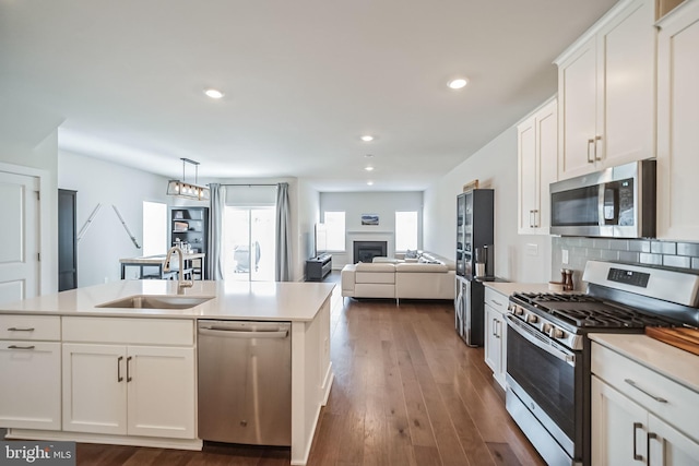 kitchen with stainless steel appliances, white cabinetry, hanging light fixtures, and sink