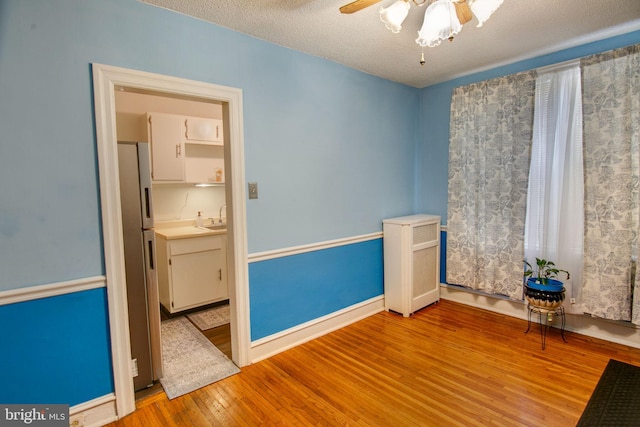 unfurnished room with a textured ceiling, light wood-type flooring, ceiling fan, and sink