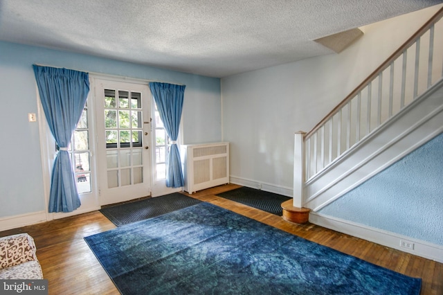 foyer entrance with dark hardwood / wood-style flooring, a textured ceiling, and radiator