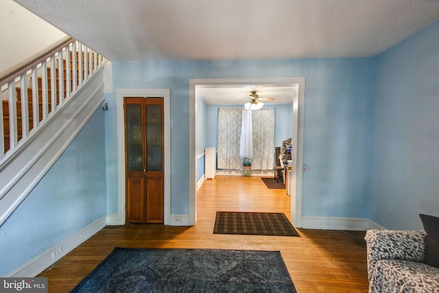 interior space featuring ceiling fan, wood-type flooring, and a textured ceiling