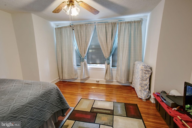 bedroom featuring hardwood / wood-style floors, ceiling fan, and a textured ceiling