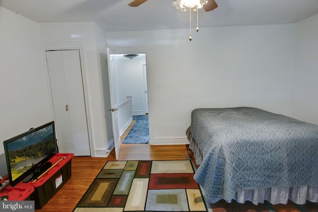 bedroom with hardwood / wood-style flooring, ceiling fan, and a closet