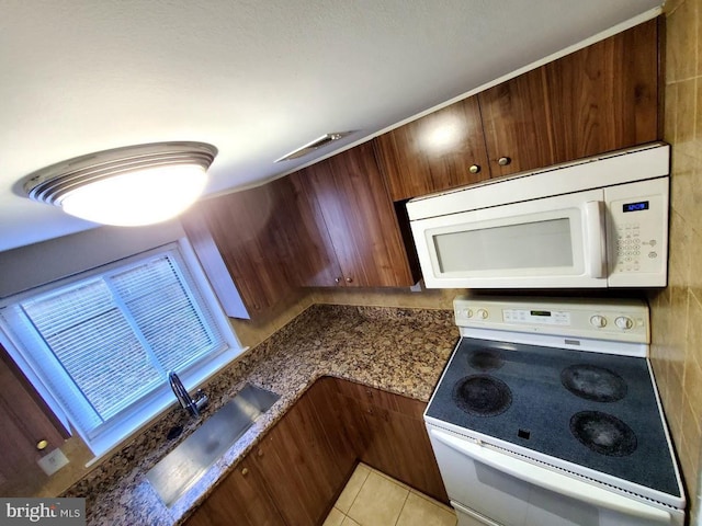 kitchen featuring sink, light tile patterned flooring, and white appliances