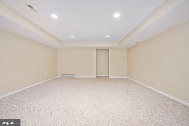 empty room featuring carpet flooring, a raised ceiling, and baseboard heating