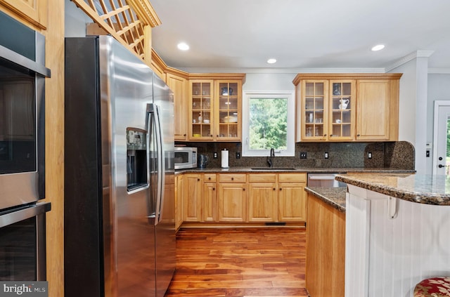 kitchen featuring backsplash, stainless steel appliances, dark stone counters, and sink