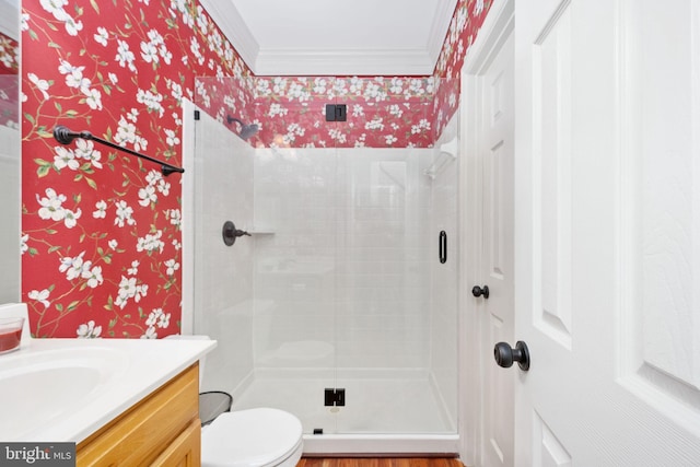 bathroom featuring vanity, toilet, ornamental molding, and a shower with door