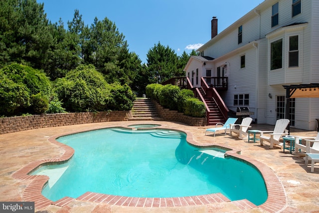 view of pool with a patio area, an in ground hot tub, grilling area, and a deck