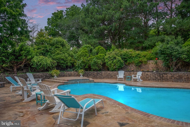 pool at dusk with a patio