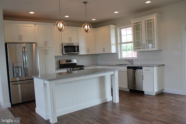 kitchen featuring light stone countertops, stainless steel appliances, white cabinets, and a kitchen island