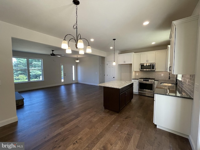 kitchen with pendant lighting, white cabinetry, backsplash, stainless steel appliances, and a kitchen island