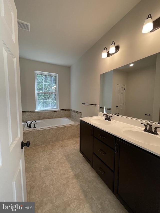 bathroom featuring vanity and tiled bath