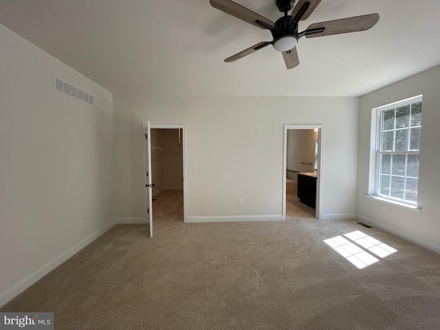 unfurnished bedroom with ensuite bath, a spacious closet, a closet, and light carpet