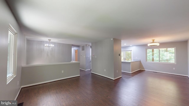 unfurnished room with a notable chandelier and dark hardwood / wood-style flooring