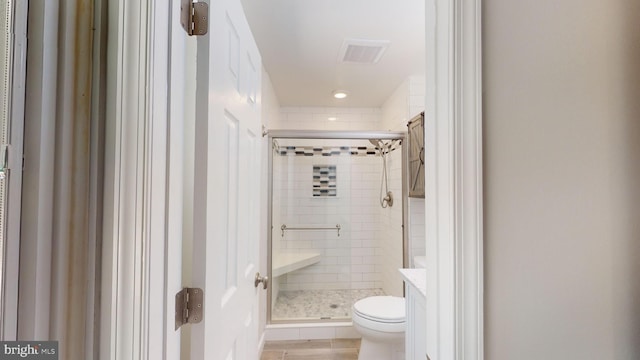 bathroom featuring a shower with shower door and toilet