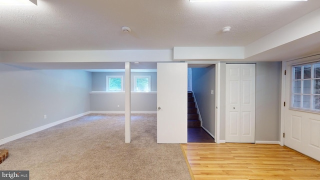 basement featuring light wood-type flooring and a textured ceiling