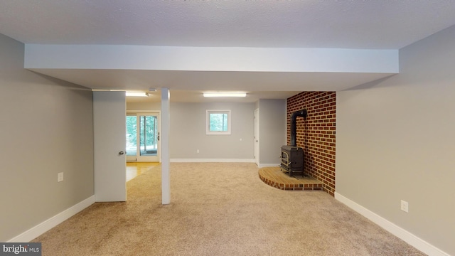 basement with light carpet, a textured ceiling, and a wood stove