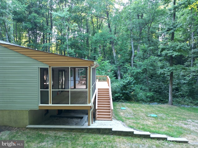 view of home's exterior with a sunroom and a lawn