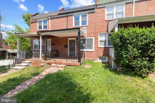 rear view of property featuring a porch and a yard