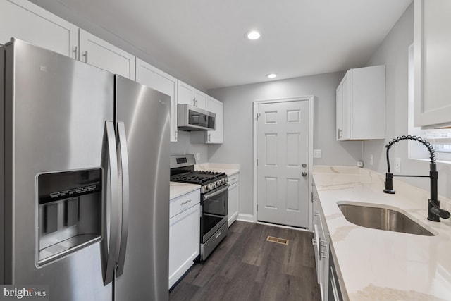 kitchen featuring light stone countertops, appliances with stainless steel finishes, white cabinetry, and sink