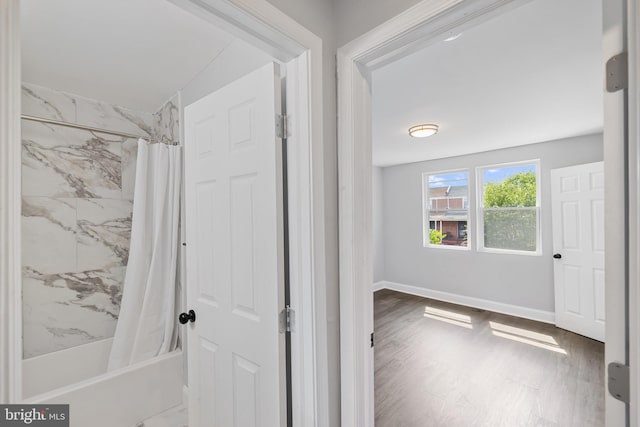 bathroom with shower / bath combination with curtain and wood-type flooring