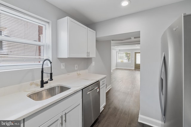 kitchen featuring light stone countertops, white cabinetry, sink, dark wood-type flooring, and stainless steel appliances