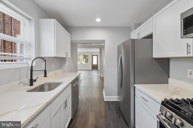 kitchen with stainless steel appliances, white cabinetry, dark wood-type flooring, and sink