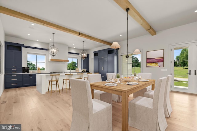 dining area featuring a chandelier, beam ceiling, light hardwood / wood-style flooring, and plenty of natural light