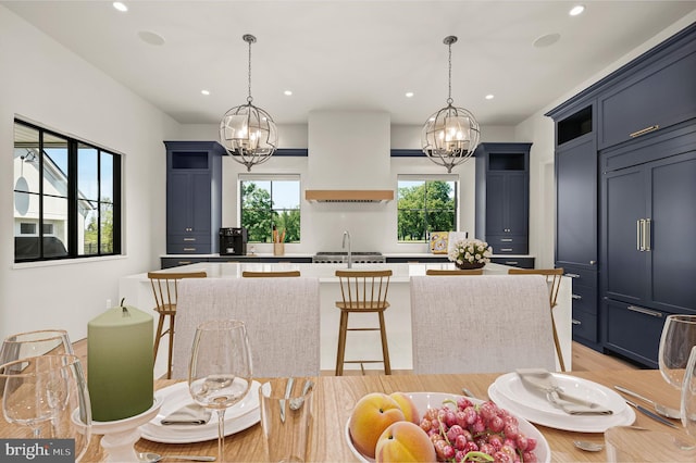 kitchen with pendant lighting, a kitchen bar, custom range hood, and a kitchen island with sink