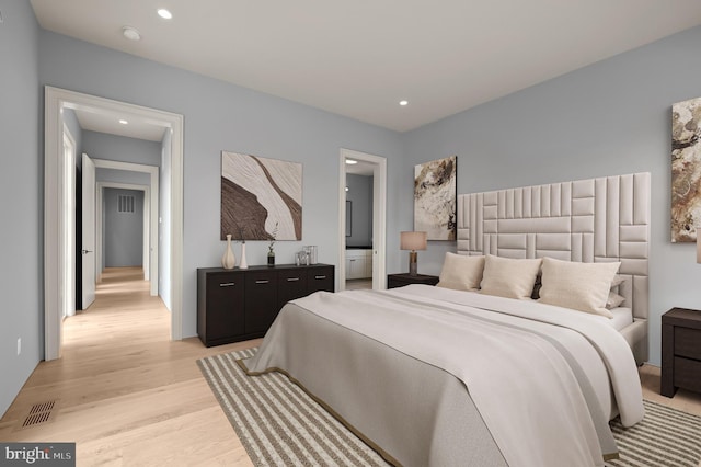 bedroom featuring ensuite bathroom and light hardwood / wood-style flooring