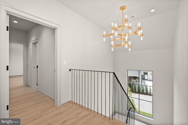 corridor featuring light hardwood / wood-style floors and an inviting chandelier