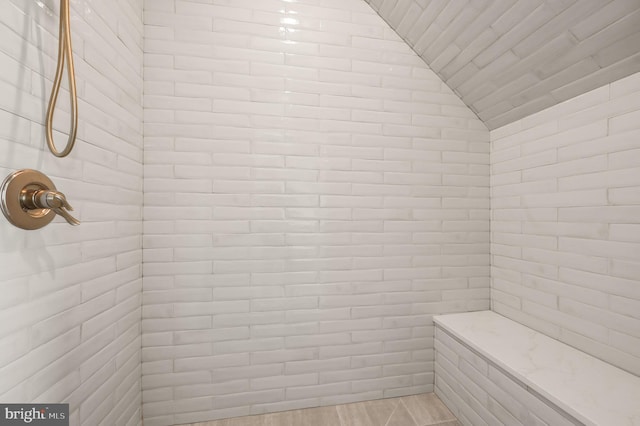 bathroom with tiled shower and vaulted ceiling