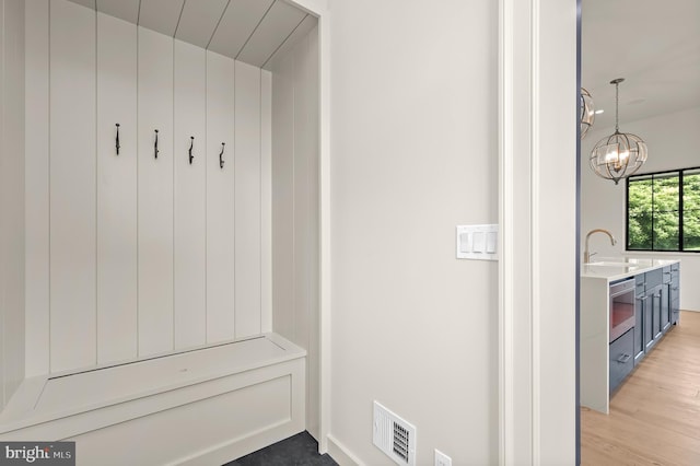 mudroom featuring sink, a notable chandelier, and light wood-type flooring