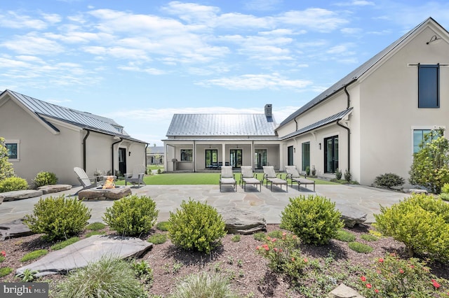 back of property with a patio area and an outdoor fire pit