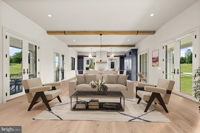 living room featuring a healthy amount of sunlight, light wood-type flooring, beam ceiling, and french doors