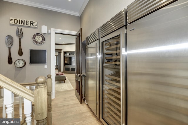 kitchen featuring wine cooler, light wood-type flooring, and ornamental molding