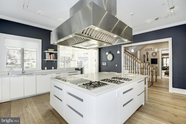 kitchen with white cabinetry, wall chimney exhaust hood, a center island, light hardwood / wood-style flooring, and sink