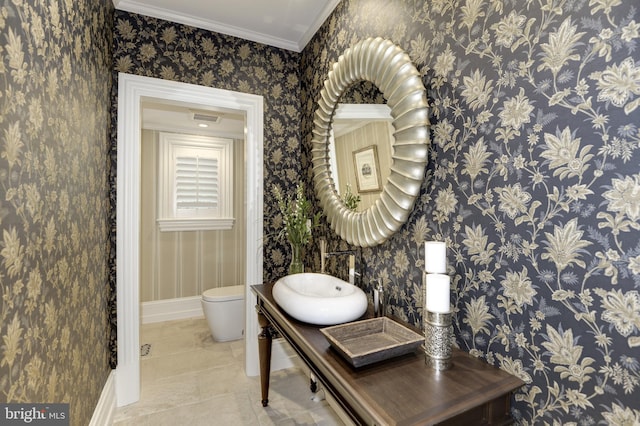 bathroom featuring ornamental molding, toilet, and sink