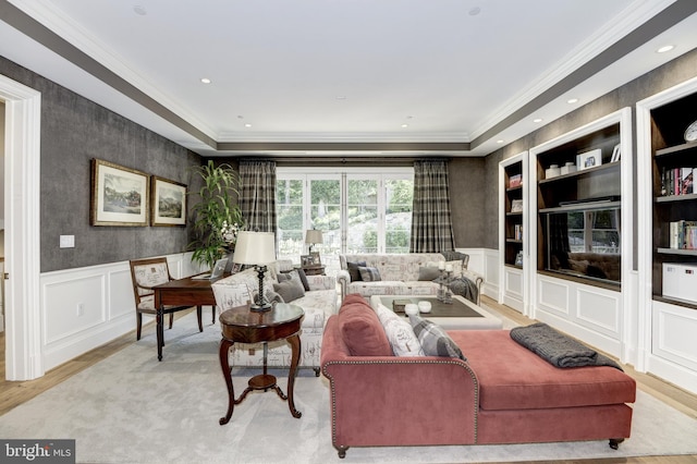 living room with ornamental molding, a tray ceiling, and light hardwood / wood-style floors