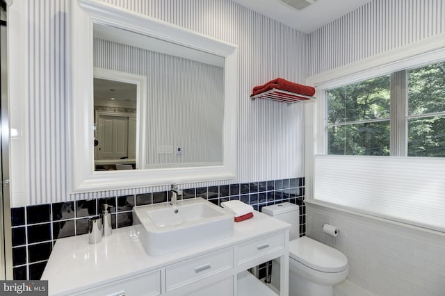 bathroom featuring vanity, tile walls, toilet, and decorative backsplash