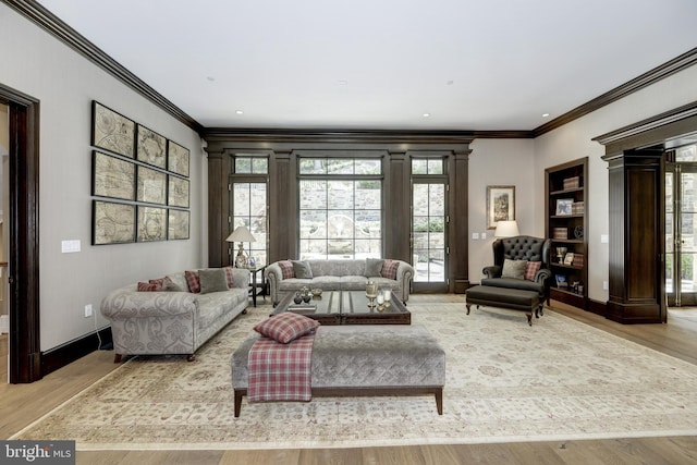 living room with light hardwood / wood-style flooring, a wealth of natural light, and crown molding