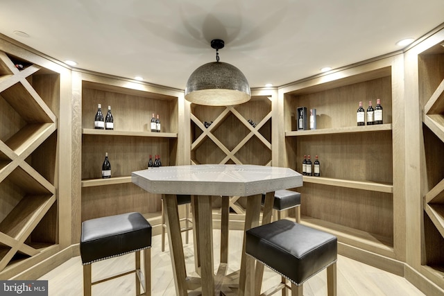 wine room with indoor bar and light hardwood / wood-style floors