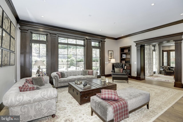 living room with ornamental molding, light wood-type flooring, and decorative columns