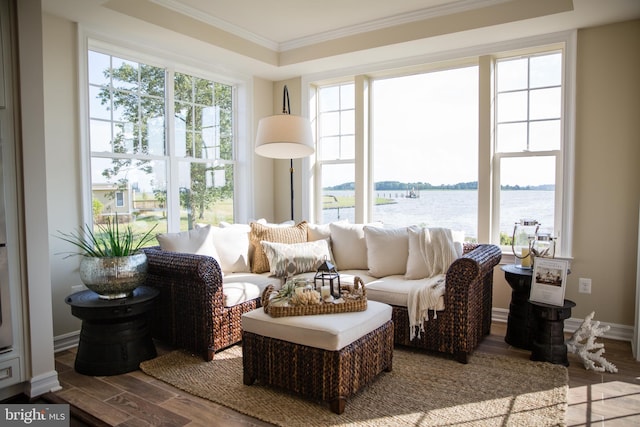 sunroom featuring a water view and a raised ceiling