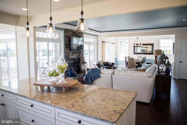 kitchen featuring white cabinetry, a stone fireplace, and hanging light fixtures