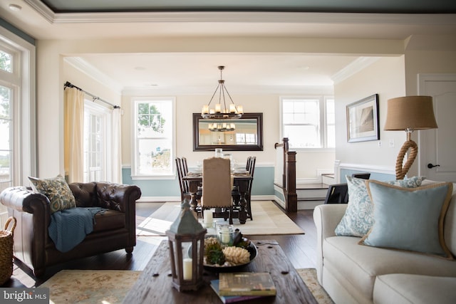 living room with an inviting chandelier, crown molding, light hardwood / wood-style floors, and plenty of natural light