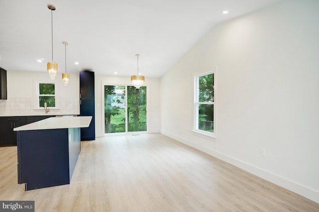 kitchen with pendant lighting, a center island, light hardwood / wood-style flooring, and tasteful backsplash