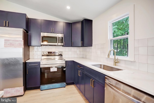 kitchen with backsplash, sink, vaulted ceiling, and appliances with stainless steel finishes