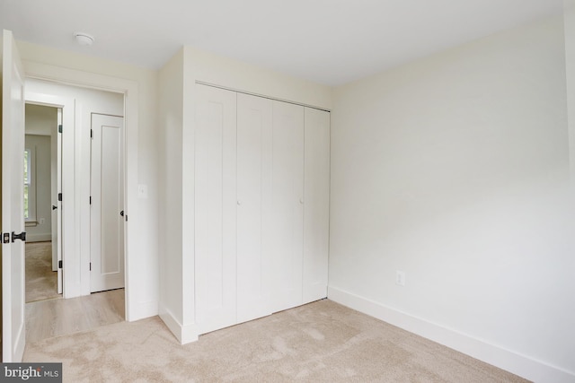 unfurnished bedroom with light colored carpet and a closet